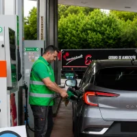Operario con chaleco verde poniendo gasolina en turismo gris en gasolinera Galp