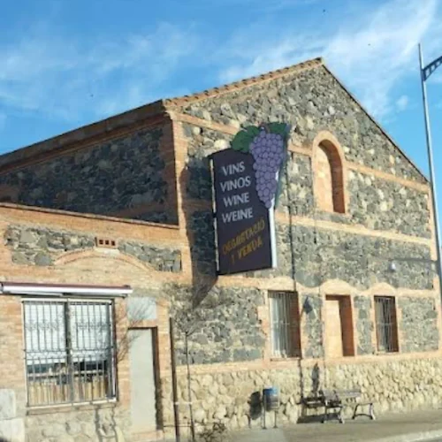 Edificio de piedra antiguo con cartel de distribución de vinos en Espolla